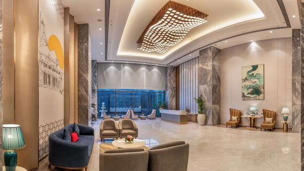 A spacious lobby with a reception desk, seating area, and a large window offering a view.