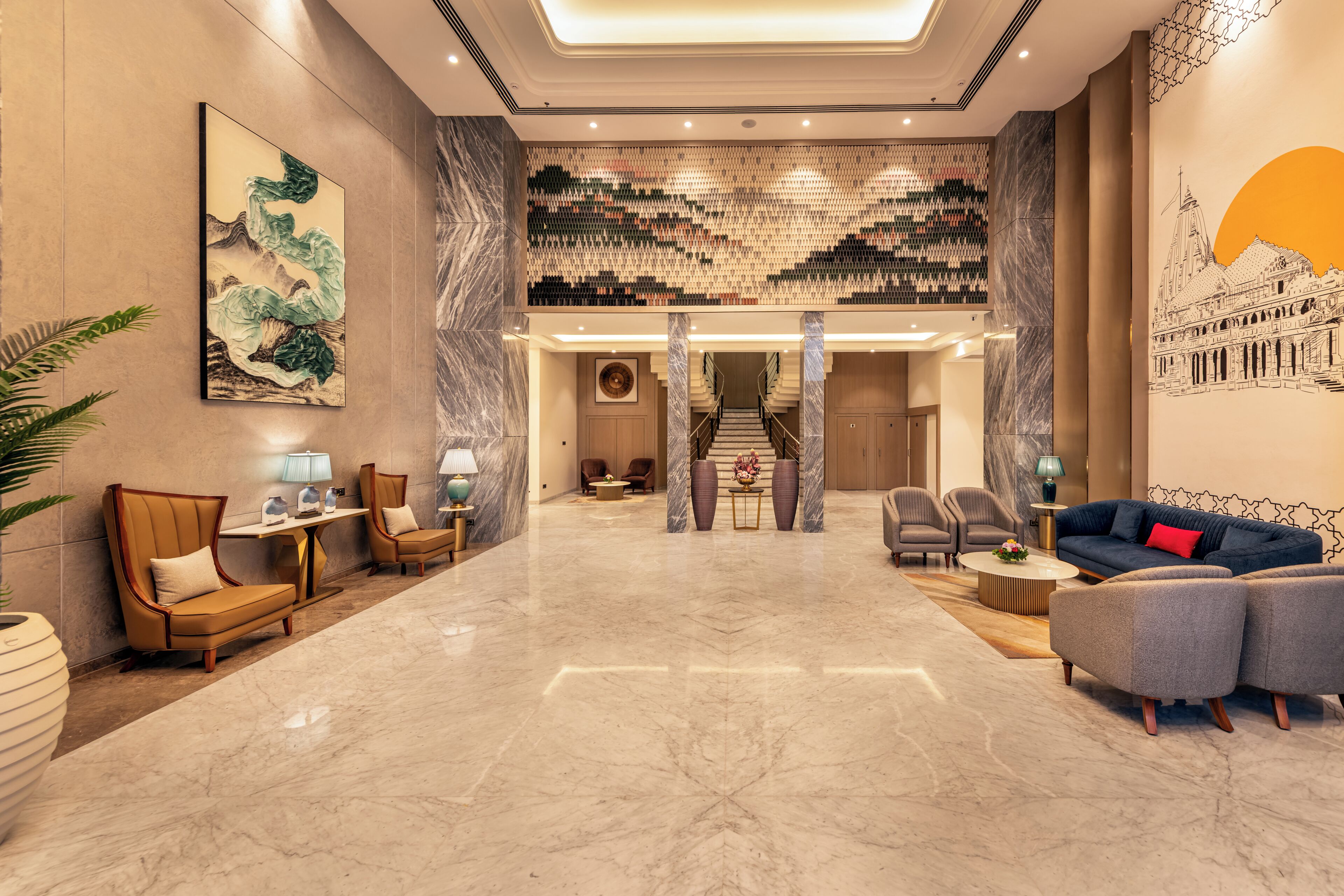 Eine großzügige Lobby mit Marmorboden, Sitzbereichen, einer Treppe und Kunstwerken an den Wänden.