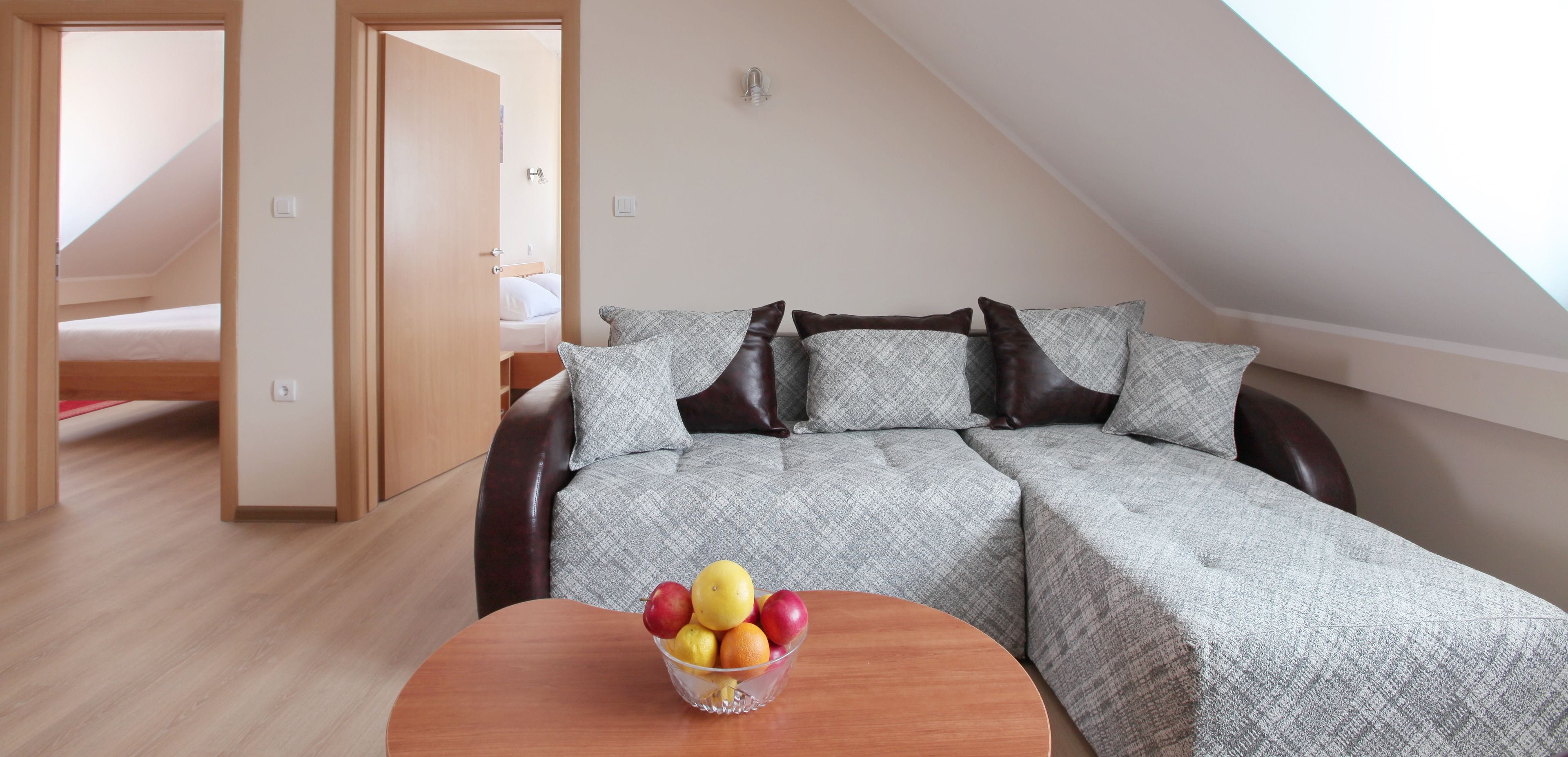 Una stanza accogliente con un letto, un divano e un tavolo con frutta.