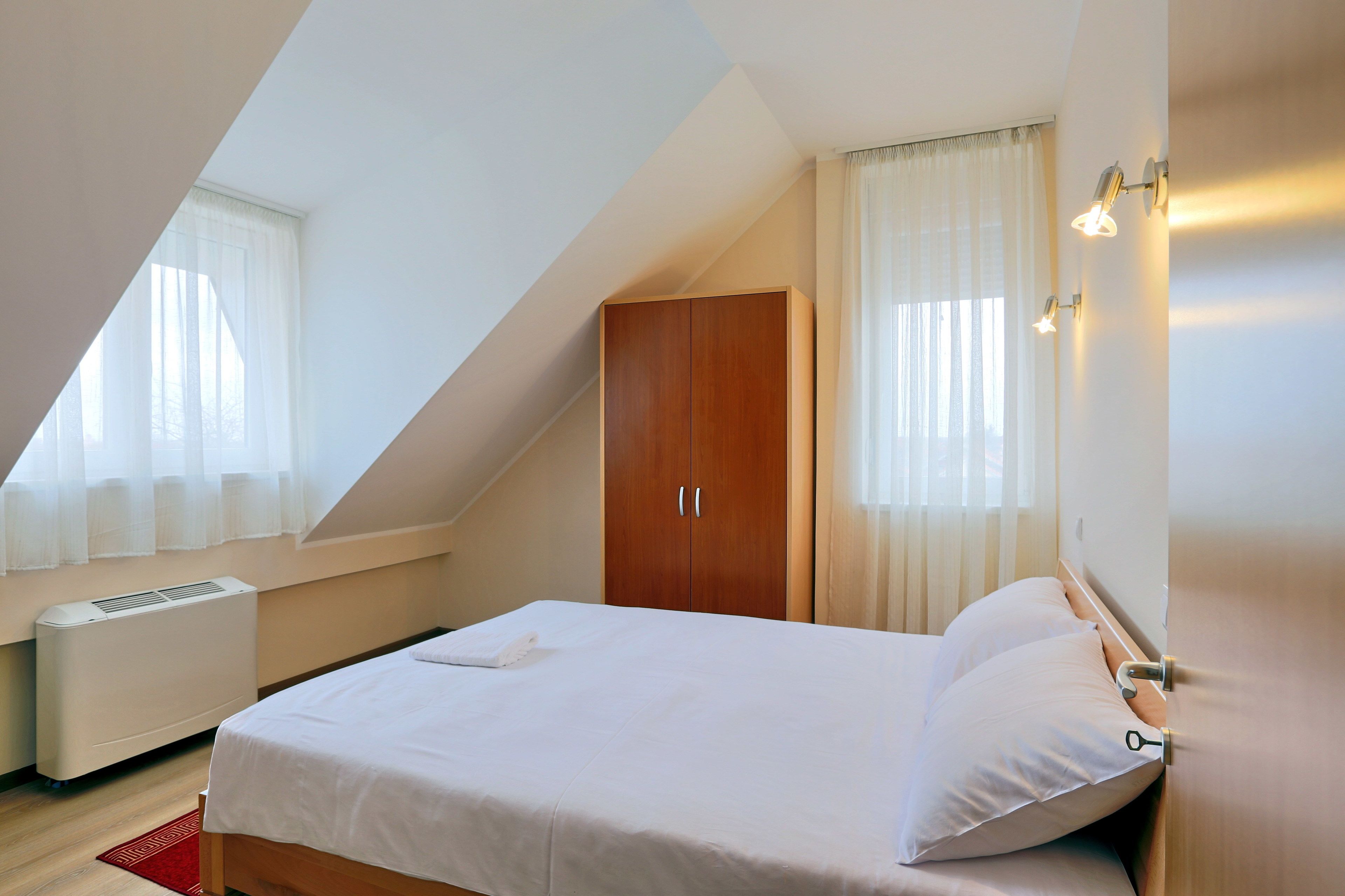 Une chambre à coucher avec un lit, une armoire et une fenêtre avec des rideaux.