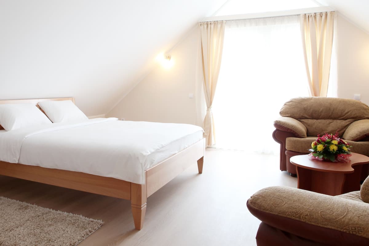 Ein Schlafzimmer mit Bett, Nachttisch, Stuhl und einem kleinen Tisch mit Blumen.