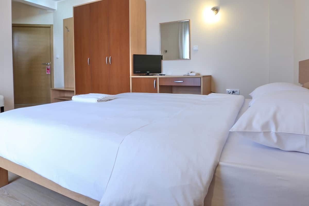 Ein Hotelzimmer mit einem großen Bett, einem Holzschrank, einem Schreibtisch mit Computer und einem Sessel.