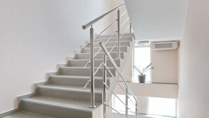 A modern interior with a staircase, a potted plant, and a large window. - Hotel Novella Uno (Novi Banovci)