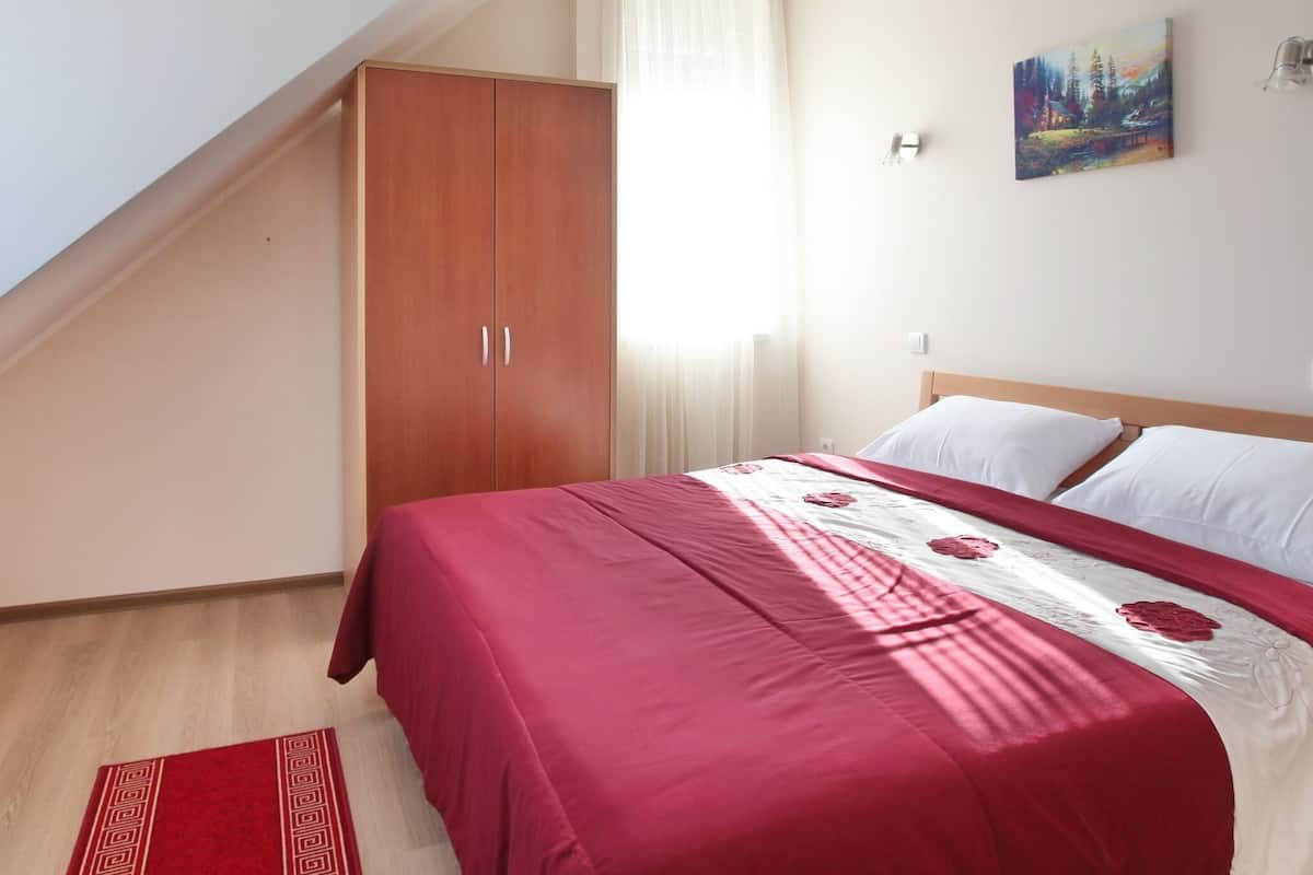 Ein Schlafzimmer mit einem Bett, einem Kleiderschrank, einem Gemälde an der Wand und einem roten Teppich.