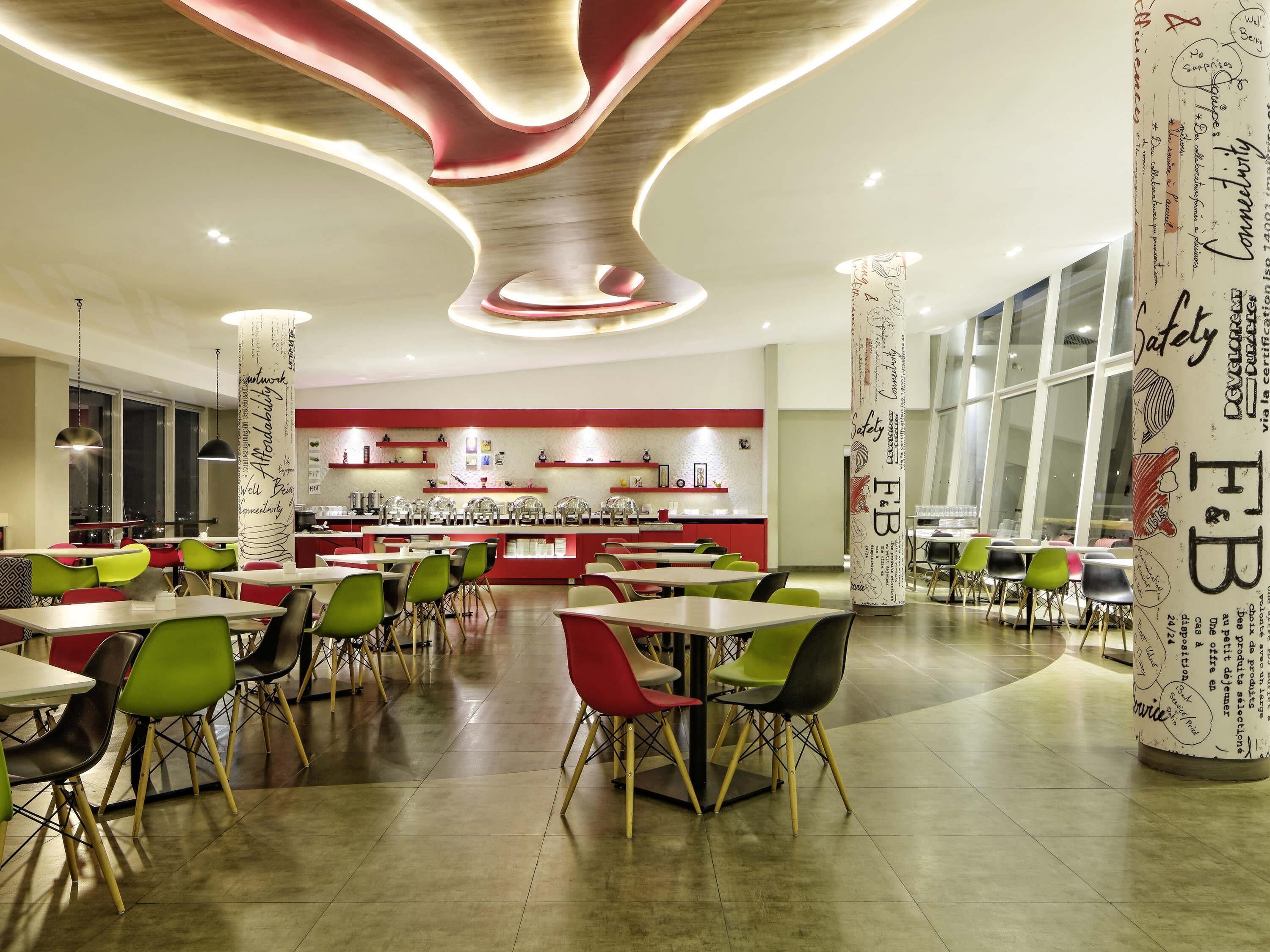 Un comedor moderno con una barra central, varias mesas y sillas, y ventanas amplias.