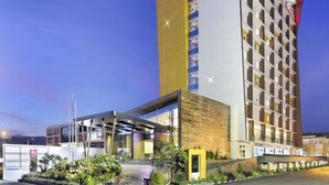 A modern hotel with a prominent 'ibis' sign, a multi-story structure, and a landscaped entrance area. - ibis Padang Hotel (Padang)