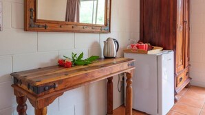 Una cuina amb taula de fusta, nevera, armari i mirall a la paret.