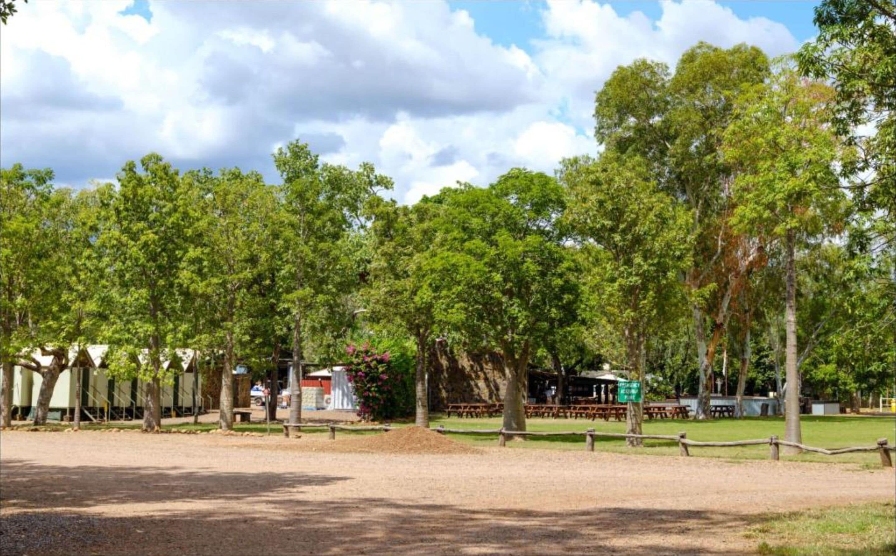 A park with picnic tables and a fenced area.