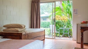 Una habitació amb un llit, una taula i caires, i vista a la verdor.