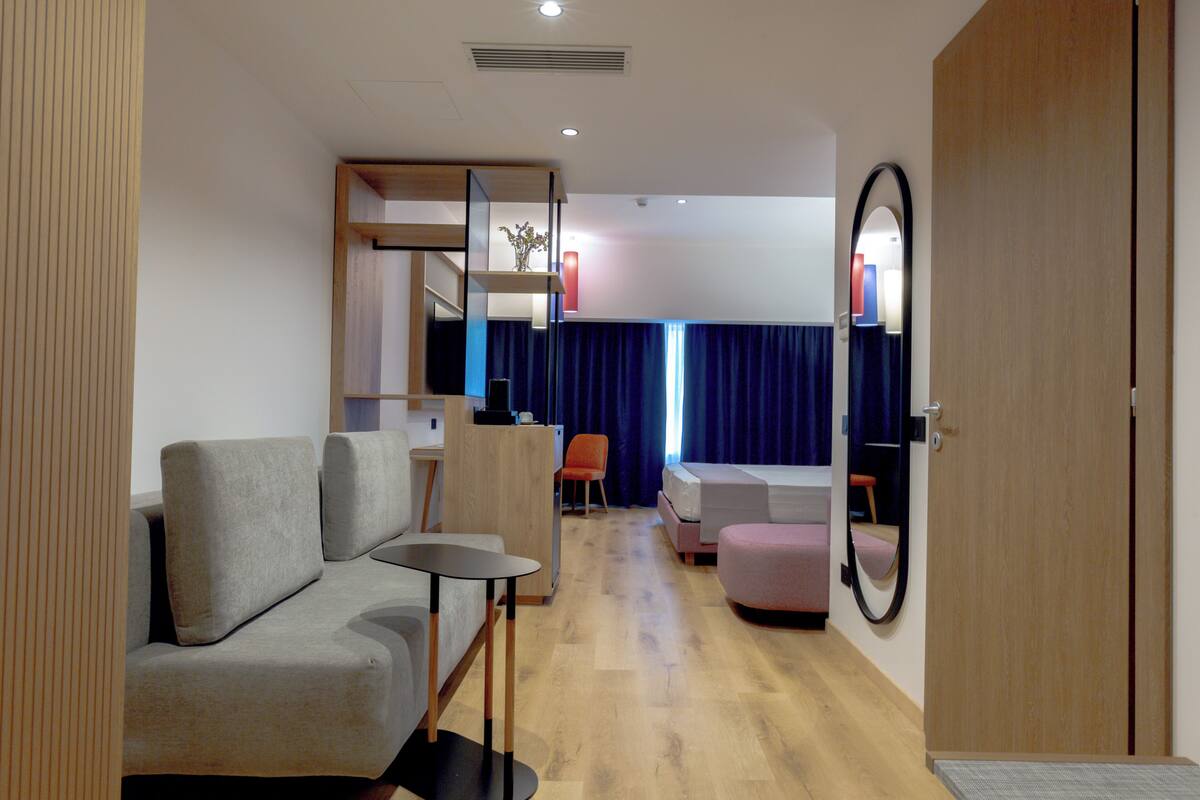 A modern interior with a sofa, a small table, a chair, and a bed.