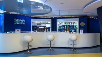 A modern bar area with a curved counter, three spherical stools, and a lounge bar sign.