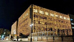 A hotel with a brick facade and multiple balconies, illuminated by warm lights.