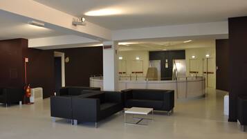 A modern lobby with black sofas, a white coffee table, and a glass partition.