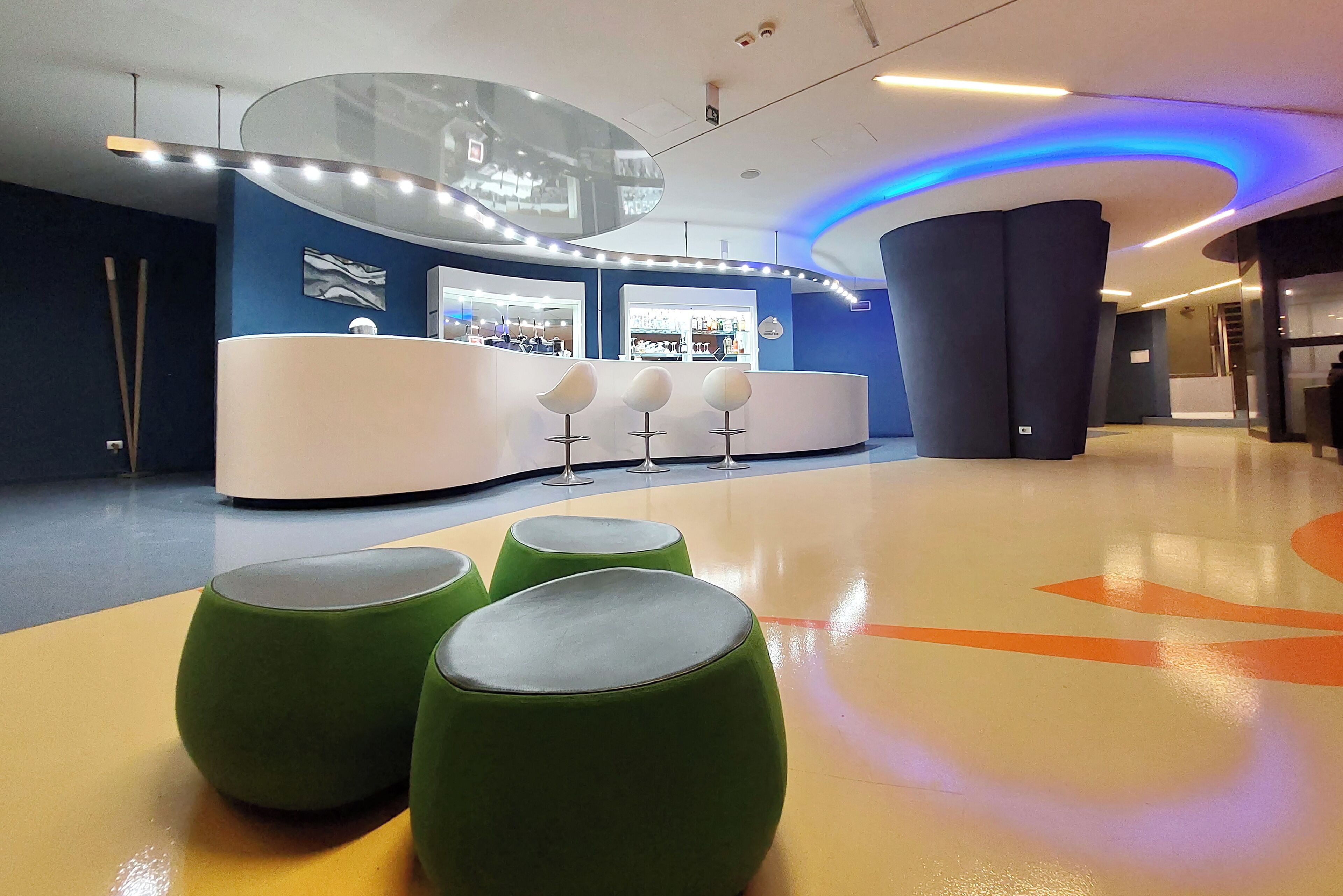 A modern lobby with a reception desk, seating area, and a curved ceiling with blue lighting.