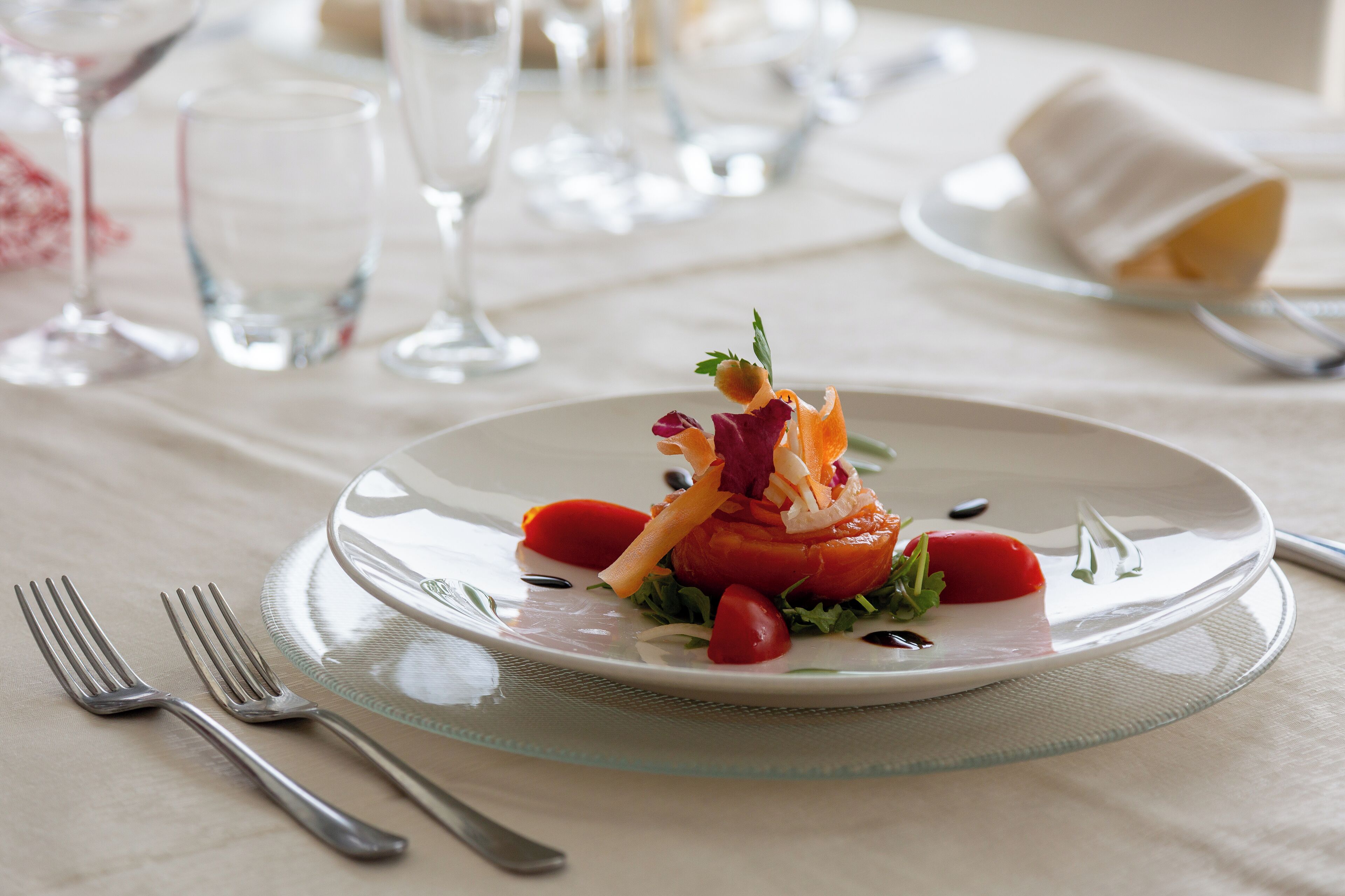 A dining table set with a white plate, silverware, and clear glassware.