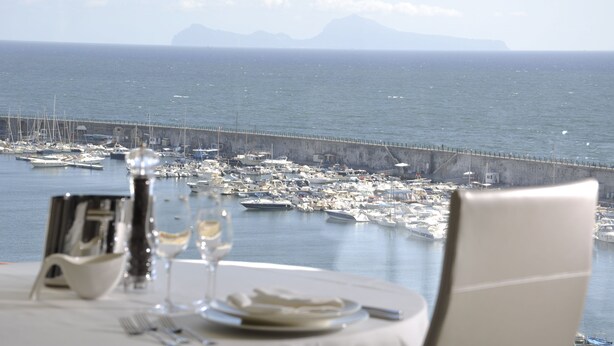 A table set for dining with a view of a marina and boats.