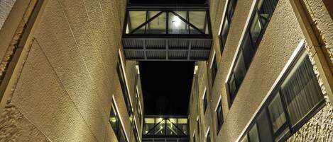 A narrow alleyway between buildings with a metal bridge overhead.