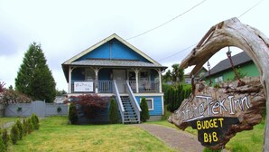 A blue house with a porch and a staircase leading to the entrance. There is a sign that reads "Tafino Trek Inn Budget B&B". - Tofino Trek Inn (Tofino)
