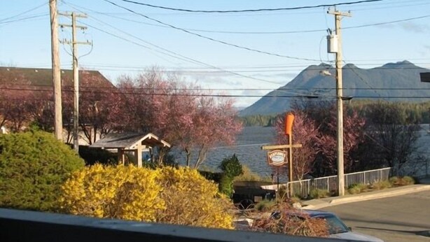 A view of a lake with mountains in the background, a small building, and a signpost. - Tofino Trek Inn (Tofino)