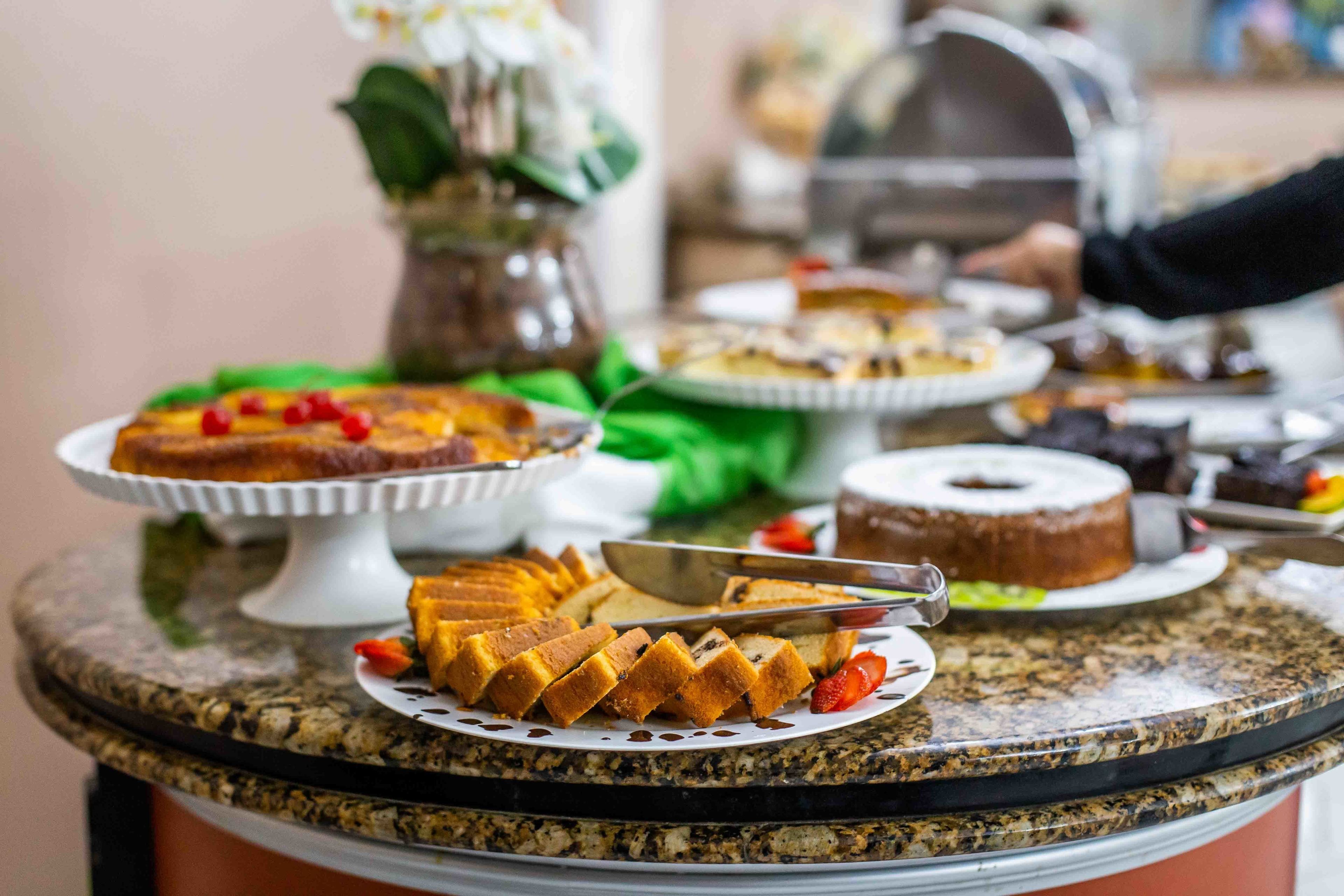 Une table de buffet garnie de divers desserts et d’un gâteau, le tout posé sur un comptoir en granit.