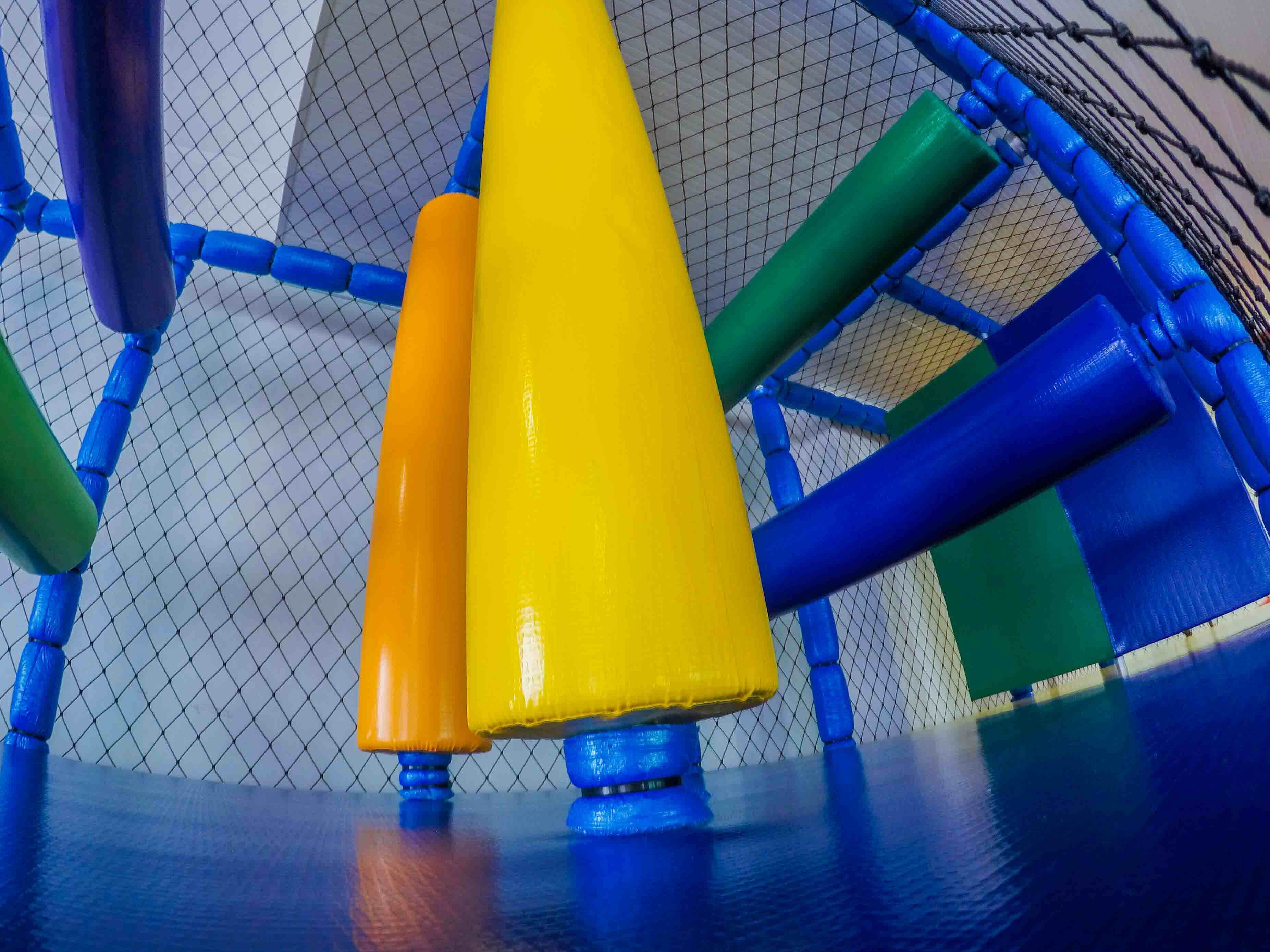 A playground structure with a netted enclosure and colorful poles.