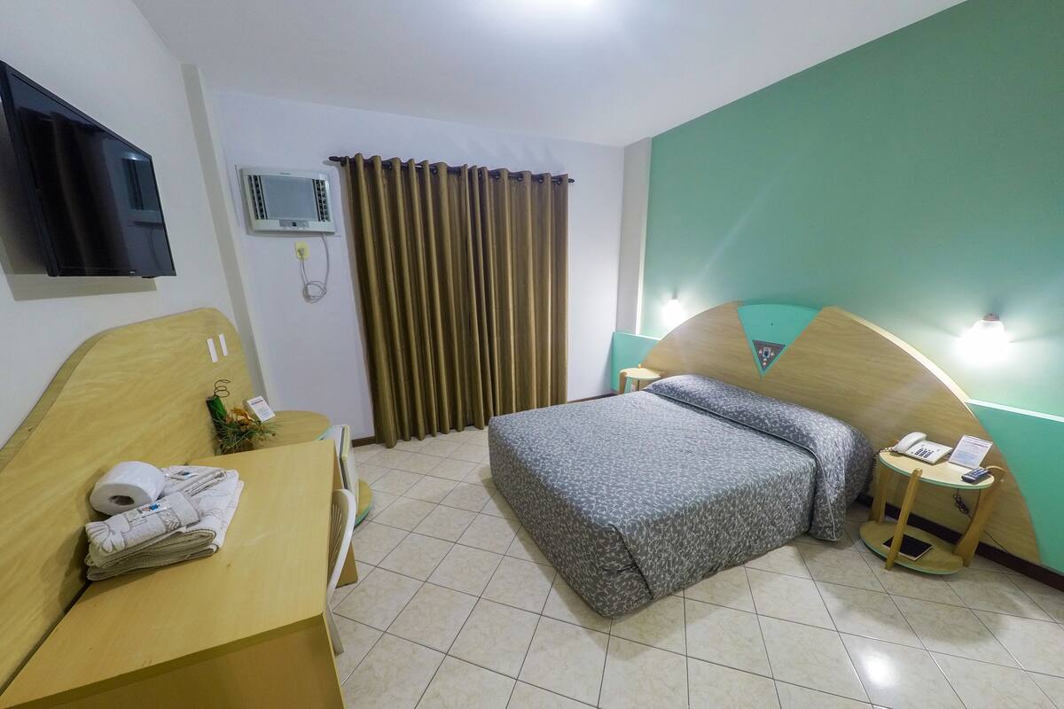 Een hotelkamer met een bed, een bureau, een stoel, een telefoon en een klein tafeltje.