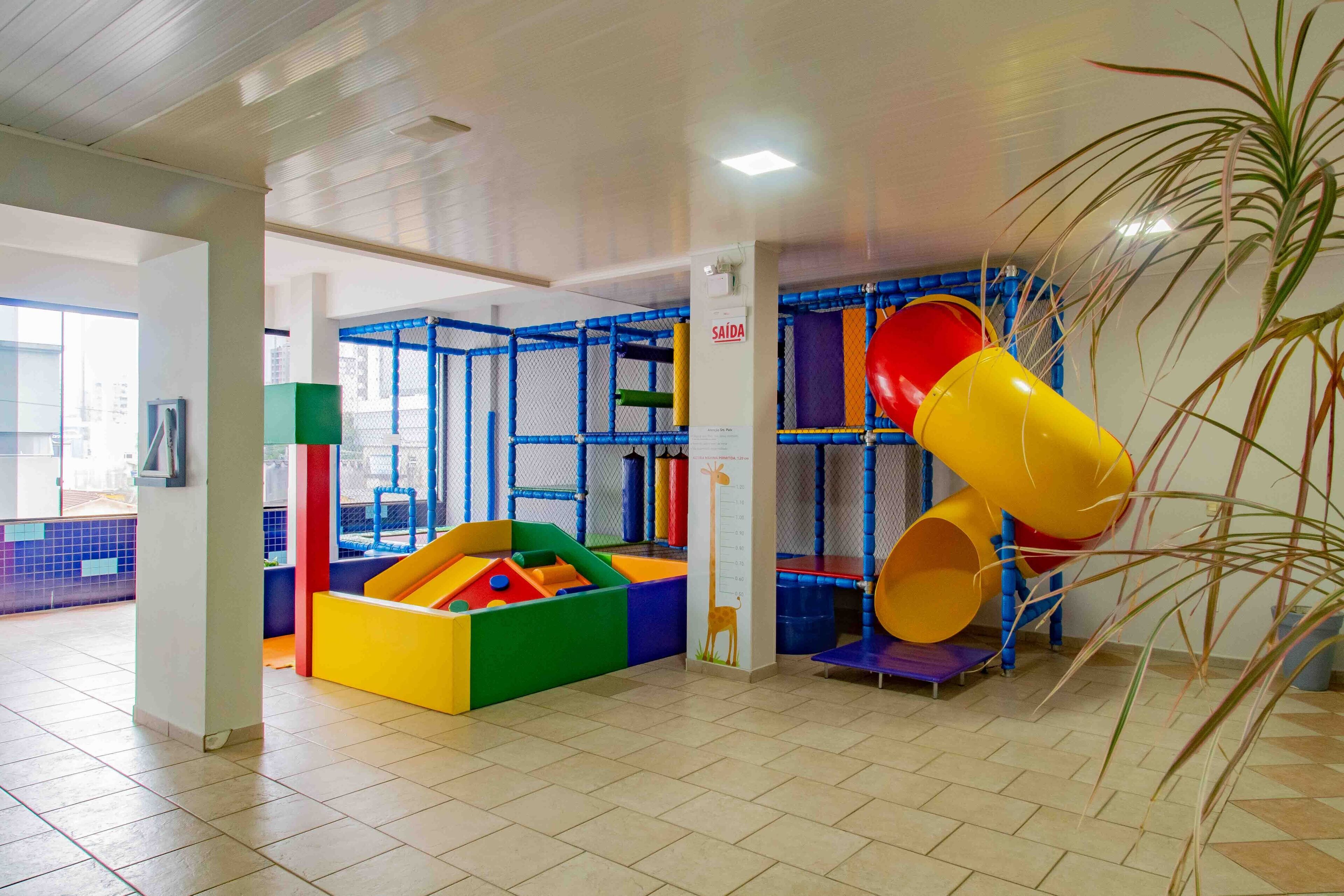A play area with colorful slides and soft play structures, surrounded by a safety net.