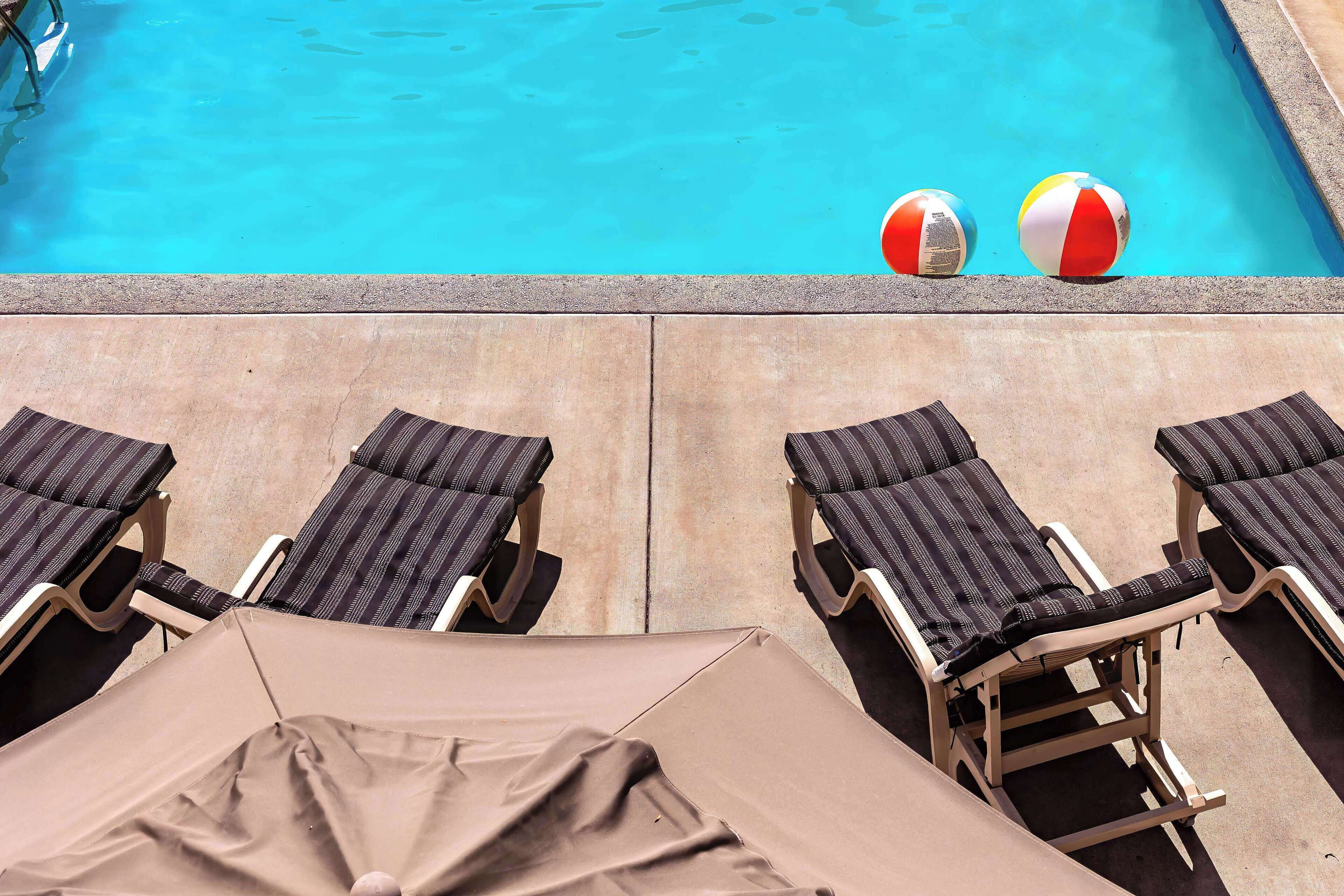 Ett poolområde med solstolar och två strandbollar.