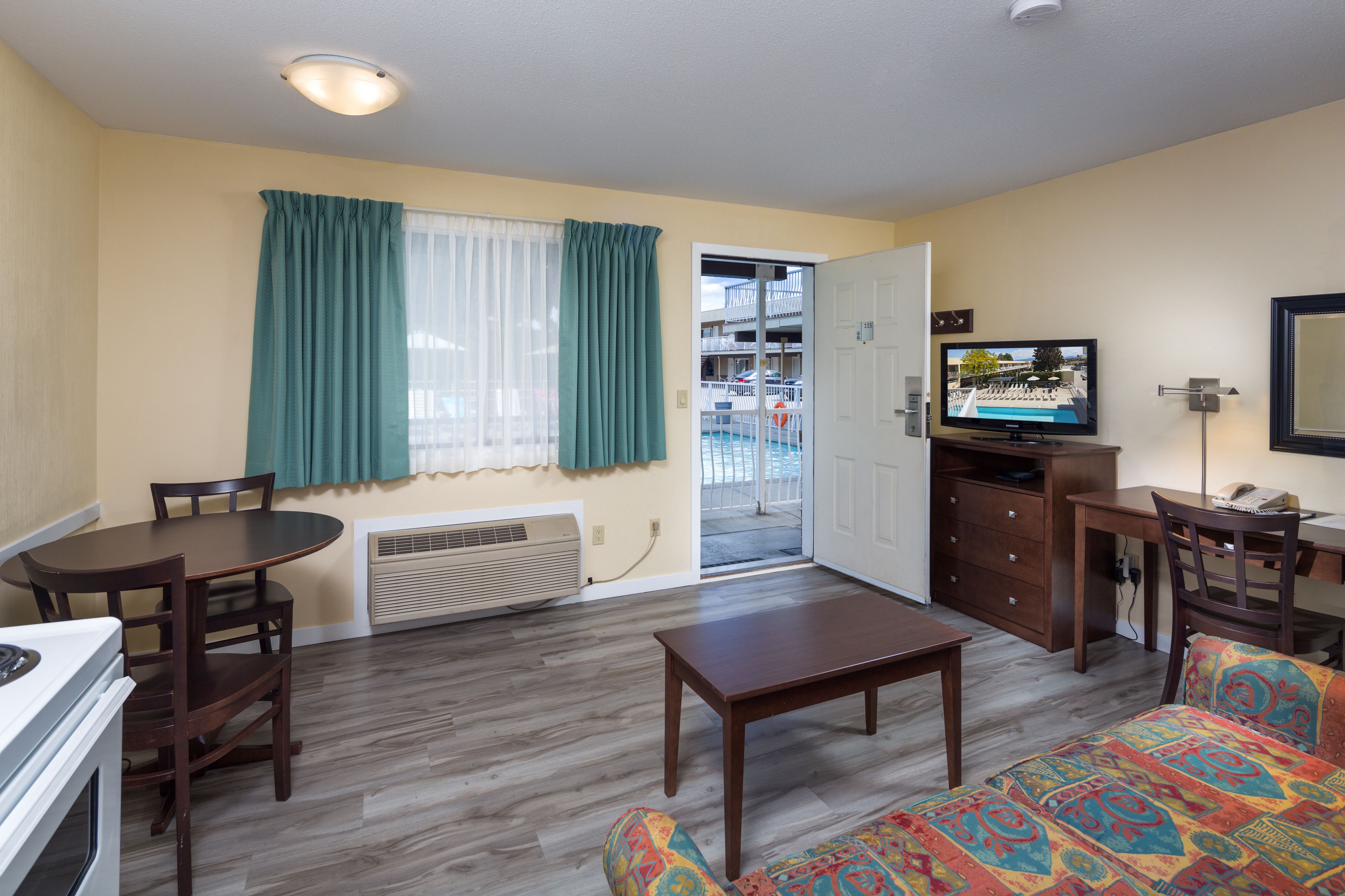 A living room with a dining table, a sofa, a TV, and a view of a balcony.