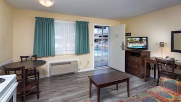 A living room with a dining table, a sofa, a TV, and a view of a balcony.