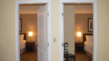 A hotel room with a bed, bedside table, chair, and a lamp.