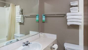 A bathroom with a sink, mirror, towel rack, toilet, and shower curtain.