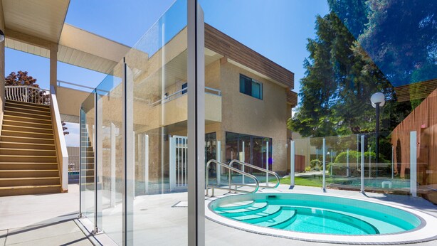Un bâtiment moderne doté d’une piscine, de rampes en verre et d’un escalier en bois.