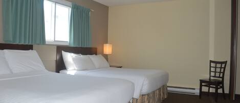 A hotel room with two beds, a nightstand with a lamp, a chair, and a window with curtains.
