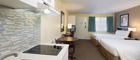 Une chambre d’hôtel équipée d’une kitchenette, de deux lits, d’un coin repas et d’une salle de bain.