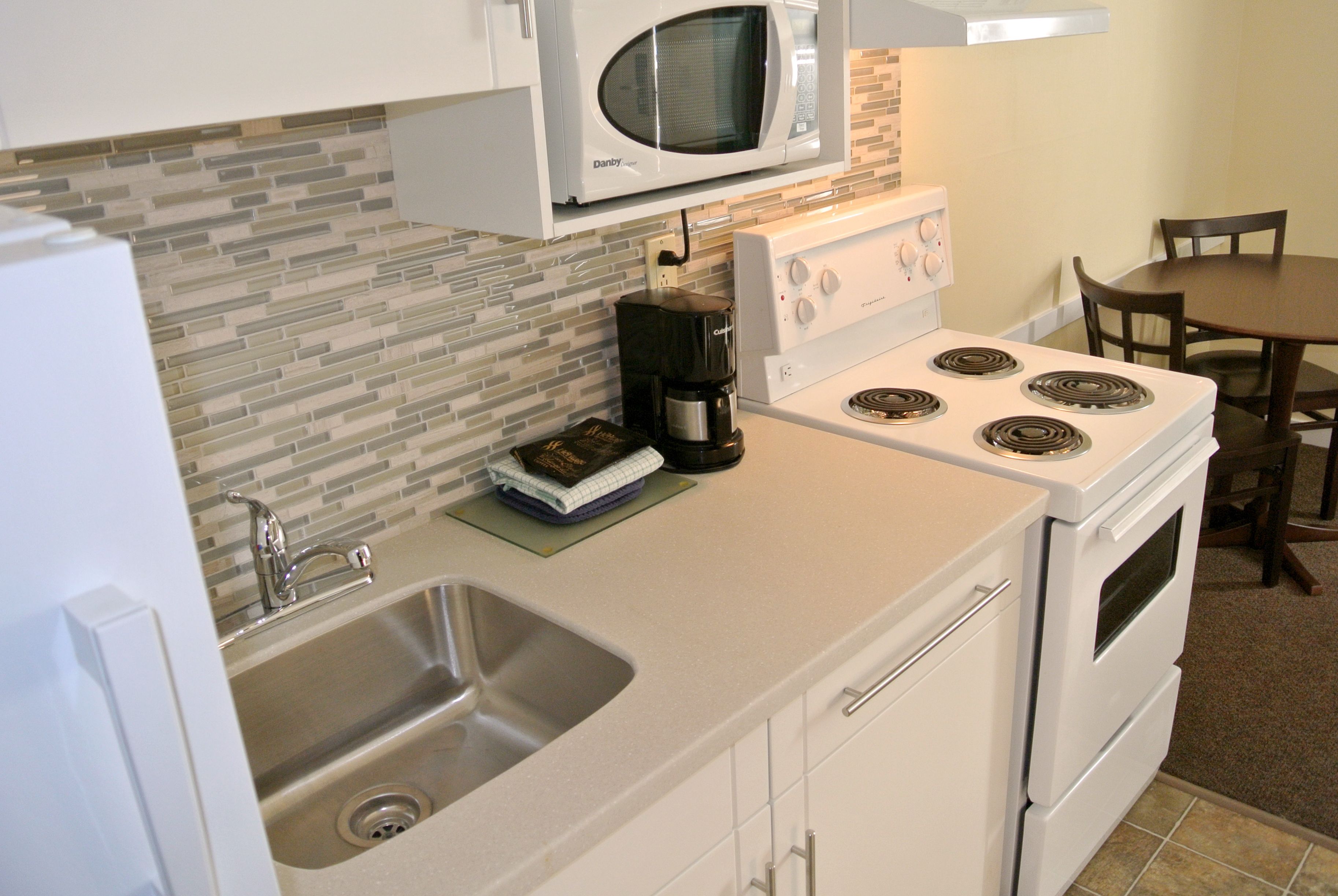 A compact kitchen with a microwave, coffee maker, sink, and stove.