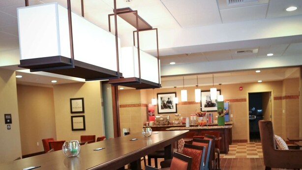A hotel dining area with a long table, multiple chairs, a bar area, and a patterned carpet.