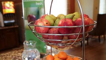 Una exhibición de frutas con manzanas y naranjas sobre una encimera de granito.