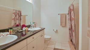 Ein Badezimmer mit zwei Waschbecken, einem Spiegel, einer Toilette und einer Duschvorhang.