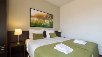 A hotel room with a large bed, two pillows, a nightstand with a lamp, and a painting on the wall.