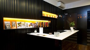 A reception desk with a display of potted plants, a clock, and informational brochures. - Riversuites (Coimbra)