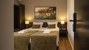 Una habitación de hotel con dos camas, un cuadro grande en la pared y lámparas de noche.
