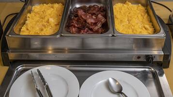 Un bufé con huevos revueltos, tocino y otro plato de huevos revueltos.