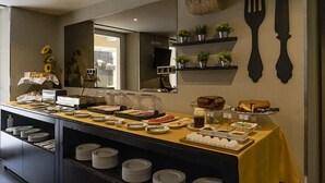 A buffet setup with various food items and a wall-mounted knife and fork decoration. - Riversuites (Coimbra)