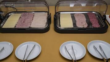 Dos vitrinas de vidrio con diversos tipos de carne y queso, acompañadas de platos blancos y cubiertos.