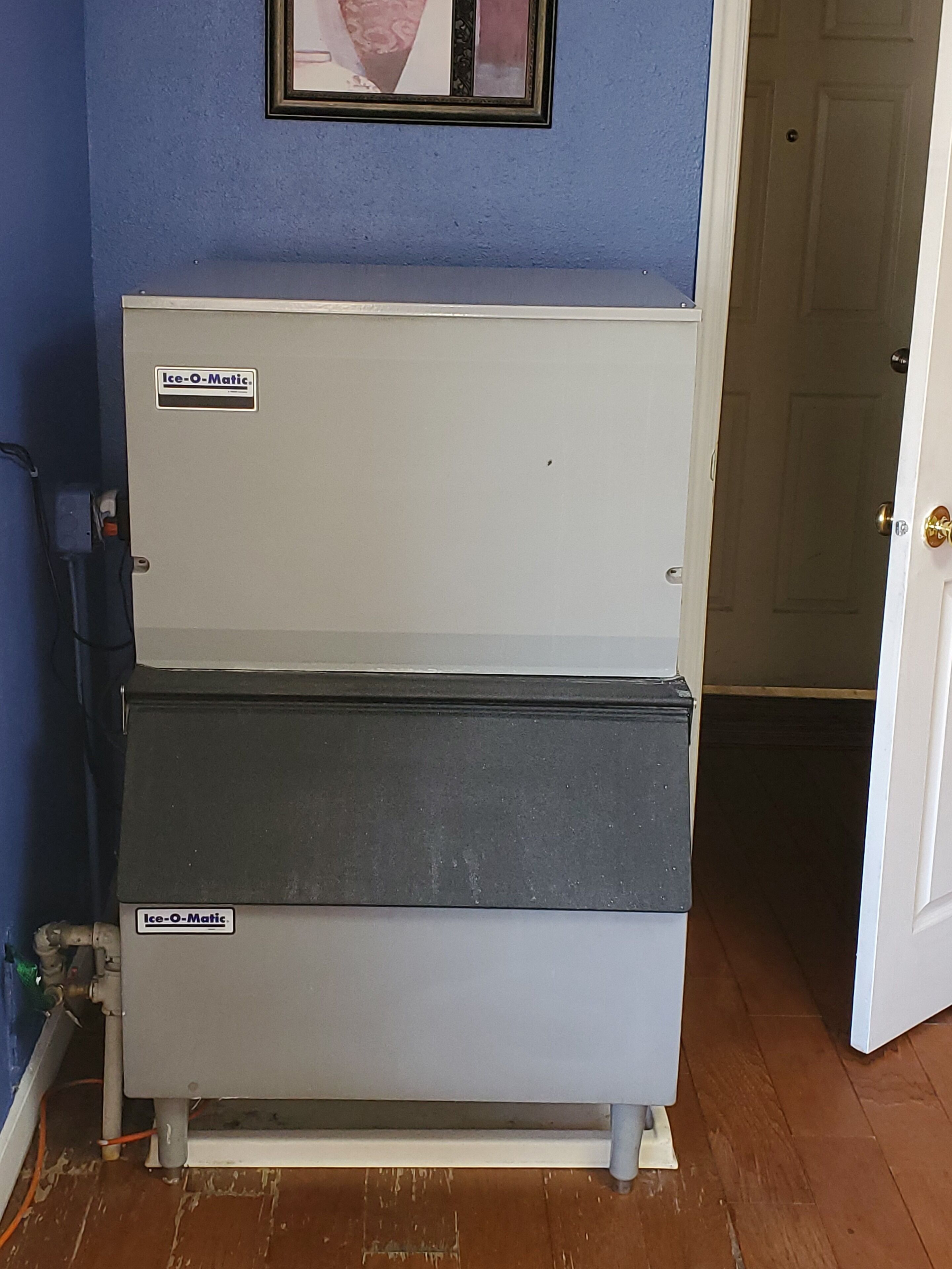 Un refrigerador blanco de Ice-Matic en una habitación con paredes azules y piso de madera.