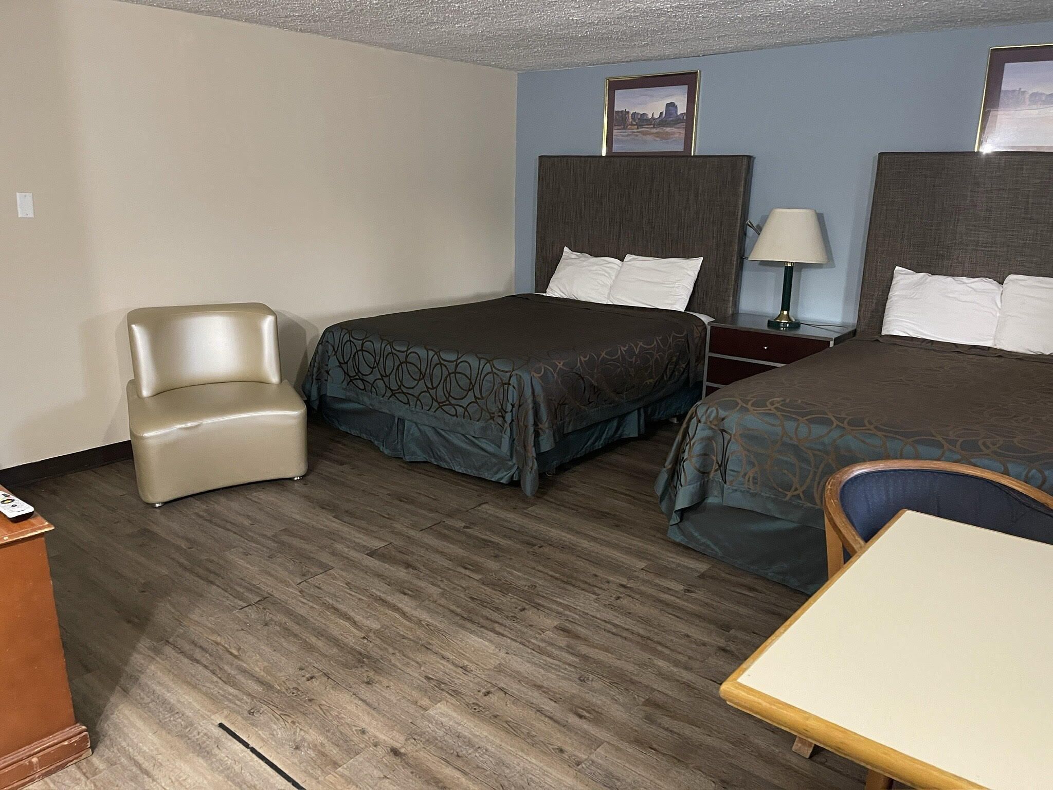 Une chambre d’hôtel avec deux lits, une chaise, une table et une lampe.