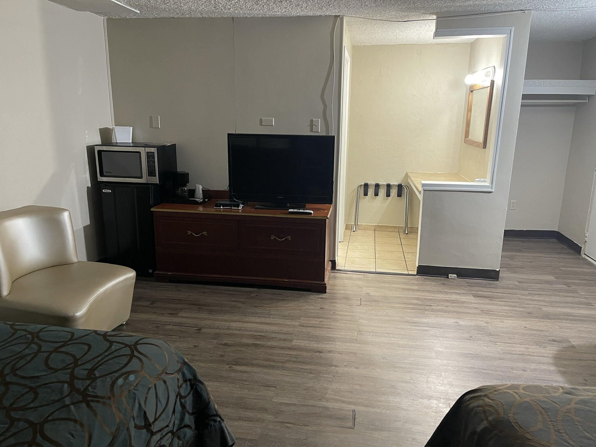 A hotel room with a bed, a TV, a small desk with a computer, and a wardrobe.