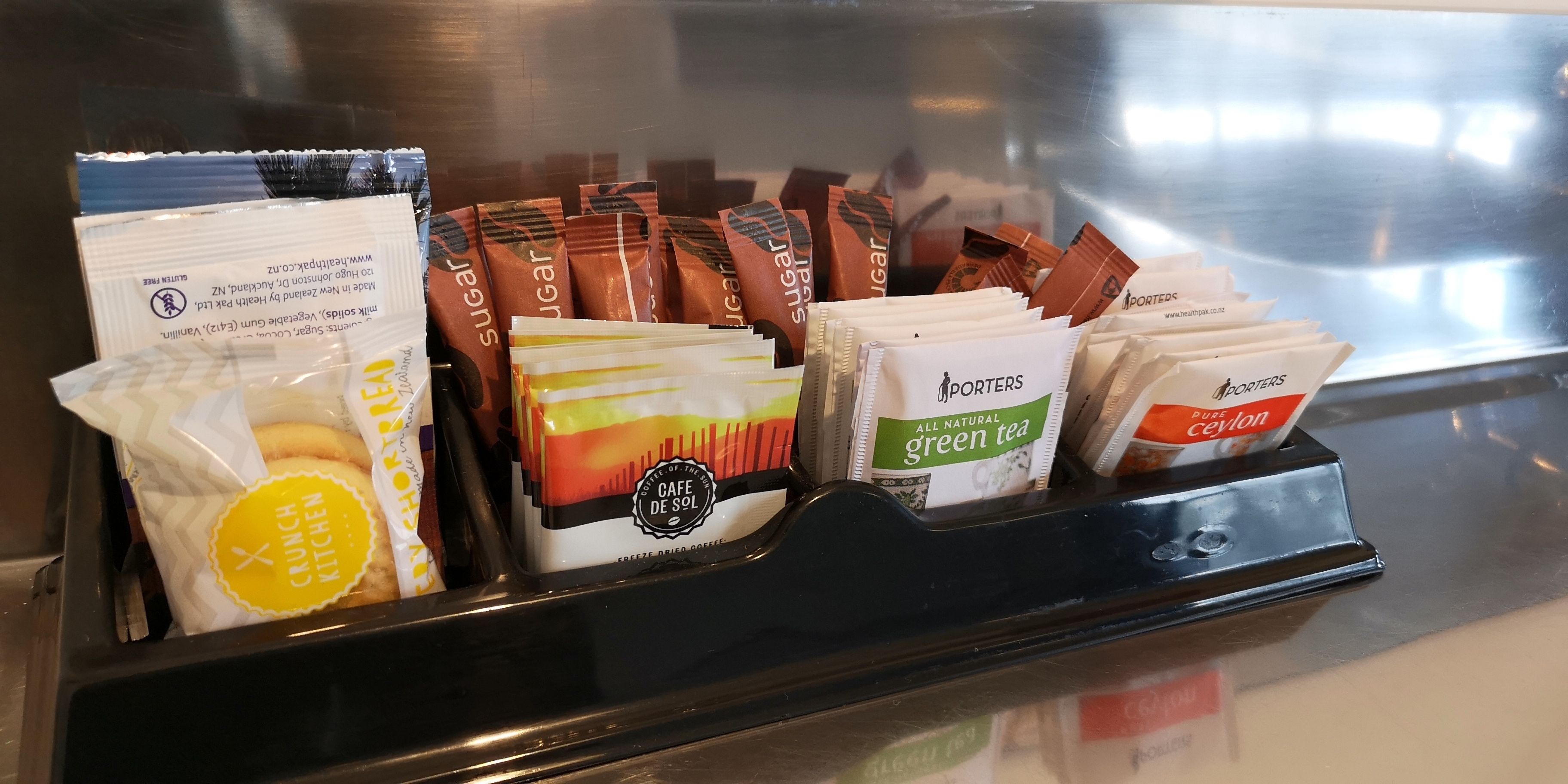 Una estación de café con diferentes productos de café envasados y un dispensador de té.