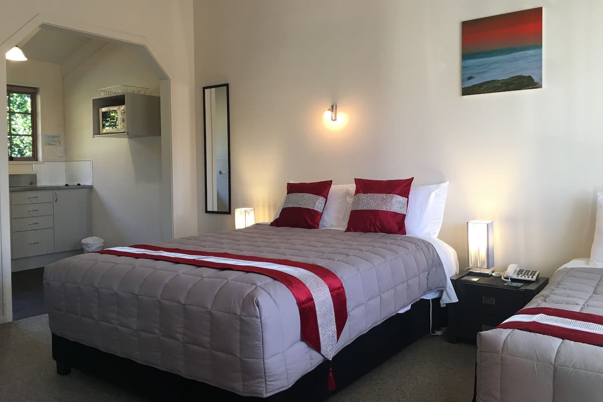 Quarto com cama, mesas de cabeceira, espelho, pintura e janela.